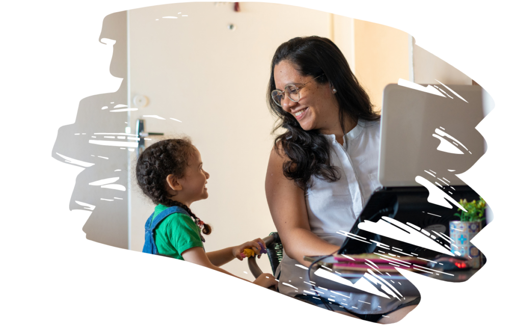 Woman with glasses smiles at a child as they sit at a desk with a laptop.